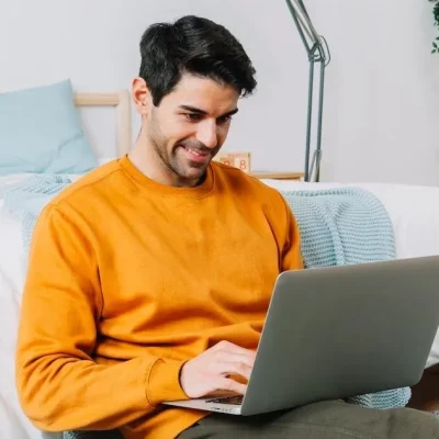 smiling-man-using-laptop-near-bed_23-2147769465-e1703099838932